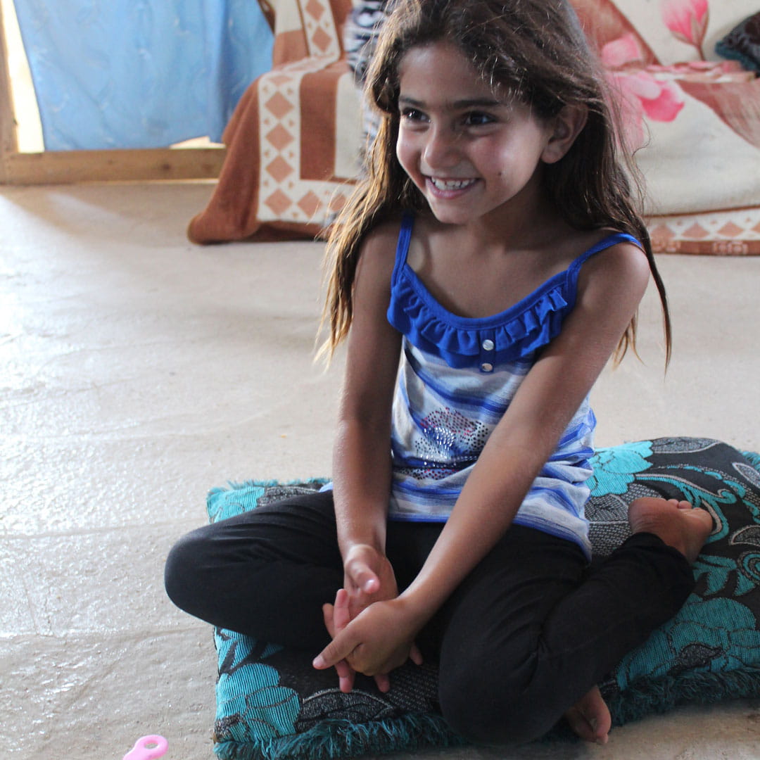 Nada, aged 8, plays with her toys in a refugee camp.
