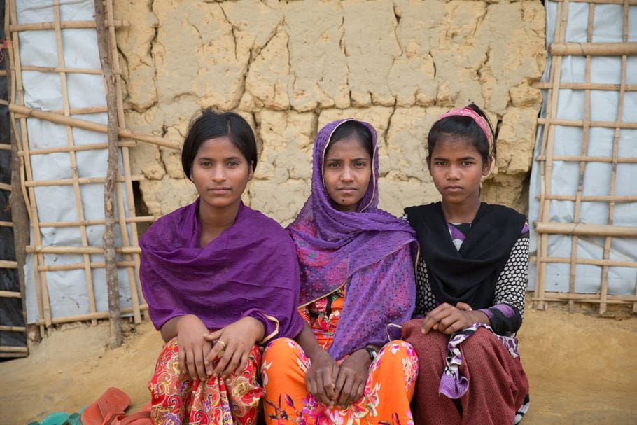 Rojeya (right, with pink hairband), sitting with two friends