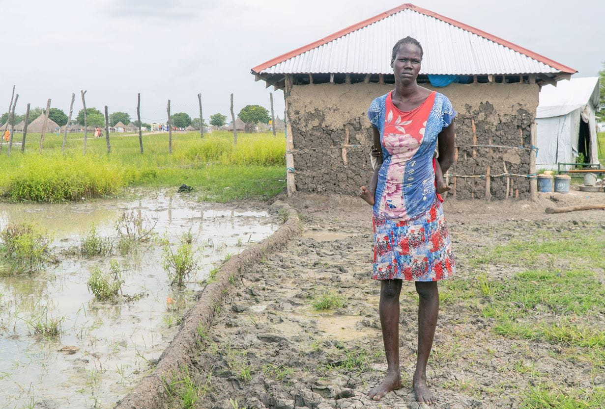Aguil, 23, lives with her two children, not far from the river Nile. When her house was overcome with floodwater, she dug trenches and built mud walls to try to redirect the flow of water. Credit: Diane Igirimbabazi/Tearfund