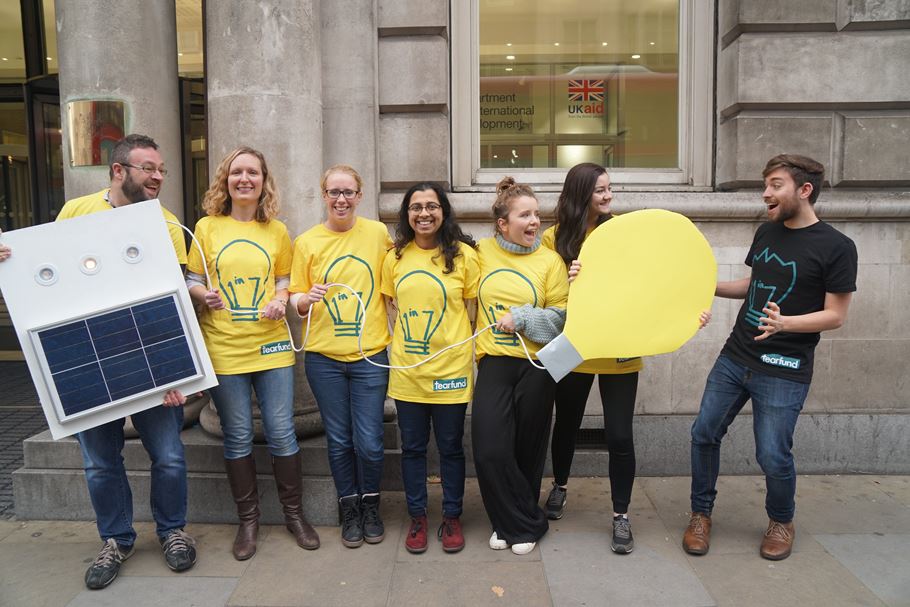 People with solar panel and giant lightbulb