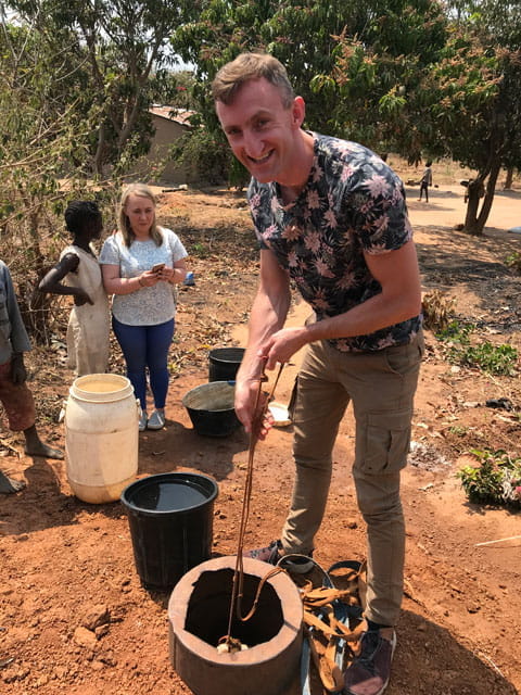 Chris drawing water from small well in Zambia