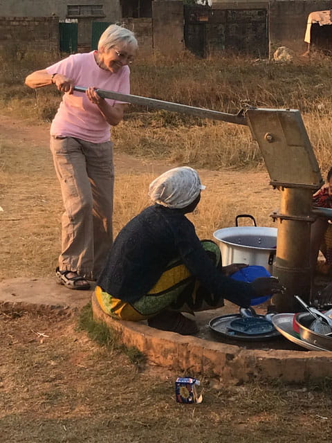 Volunteer draws water with pump