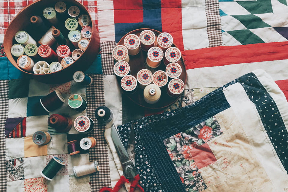 Quilt with reels of cotton.