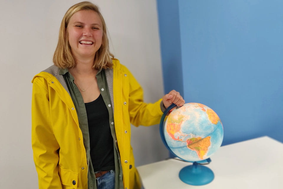 Natalie stands by a globe