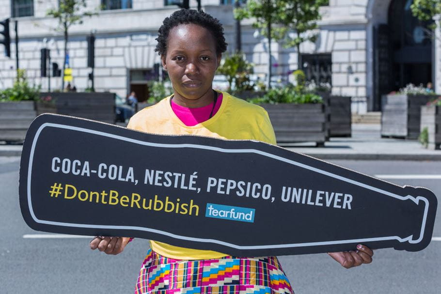 Girl holds up bottle shaped Rubbish Campaign placard.