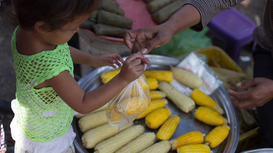 A child holds a bag of corn at a street market in Cambodia. Credit: Ralph Hodgson/Tearfund