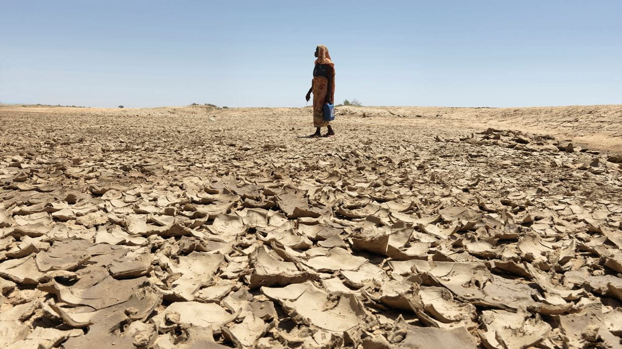 A man searches for clean water on a parched river bed