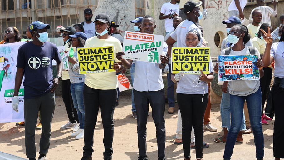 A group of Nigerian men and women hold signs advocating for climate justice during a protest.