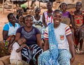 A group of people are sat outside. Two people are in the foreground smiling.