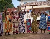 A group of women stand next to each other in a line and hold their hands in the air.