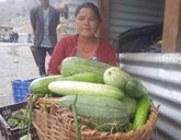 A Nepalis woman holding a large basket of fruit.