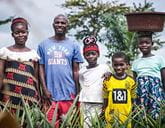 A smiling family standing in long grass