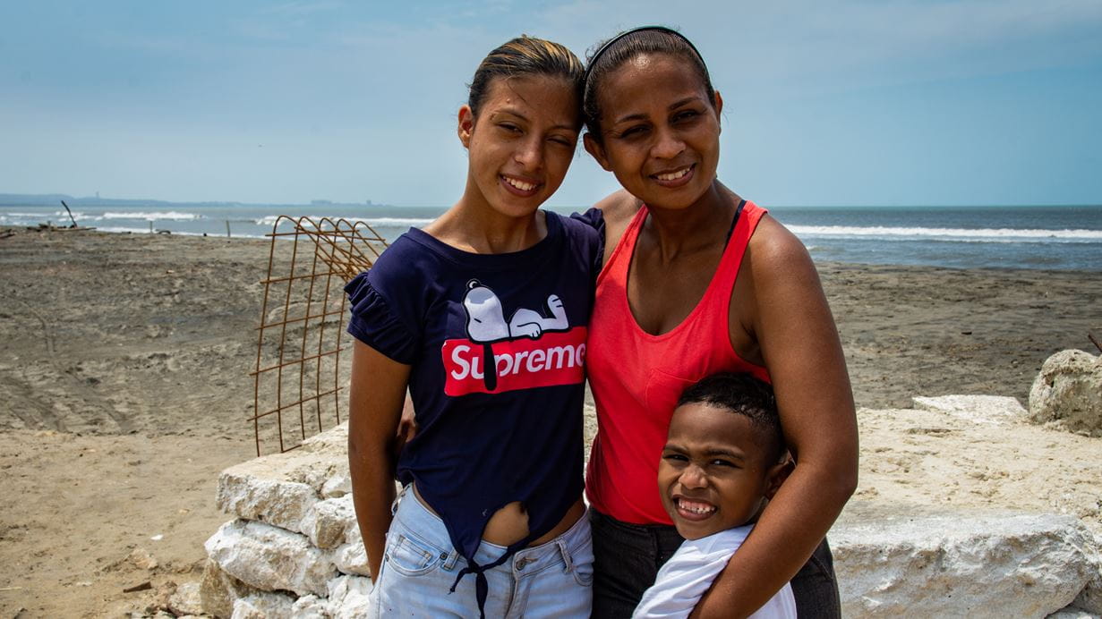 A smiling woman at a beach with her two children children