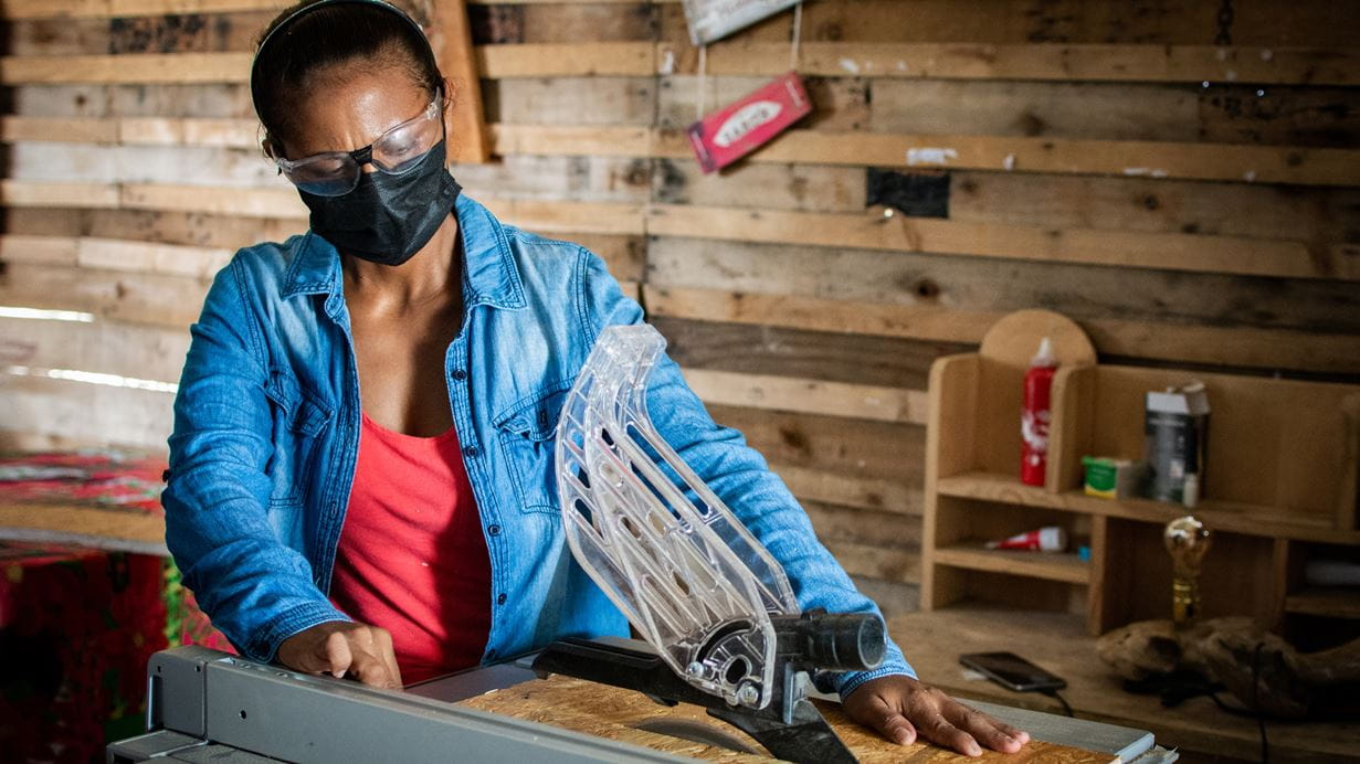 A woman using a wood cutting table saw