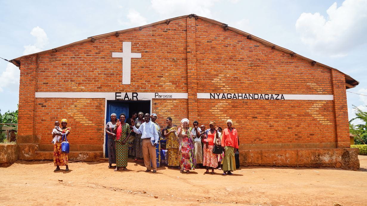 A group of people standing outside a brick church building