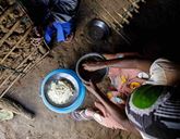 A birds eye view of a woman cooking with several bowls on the ground.