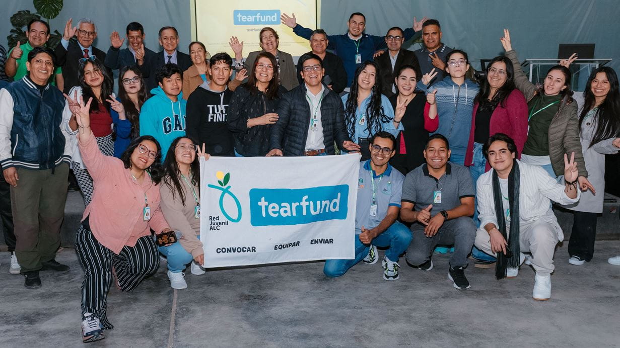 Group photo of Tearfund staff and young people holding a banner with the Tearfund logo.