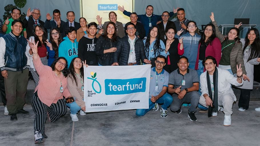 Group photo of Tearfund staff and young people holding a banner with the Tearfund logo.