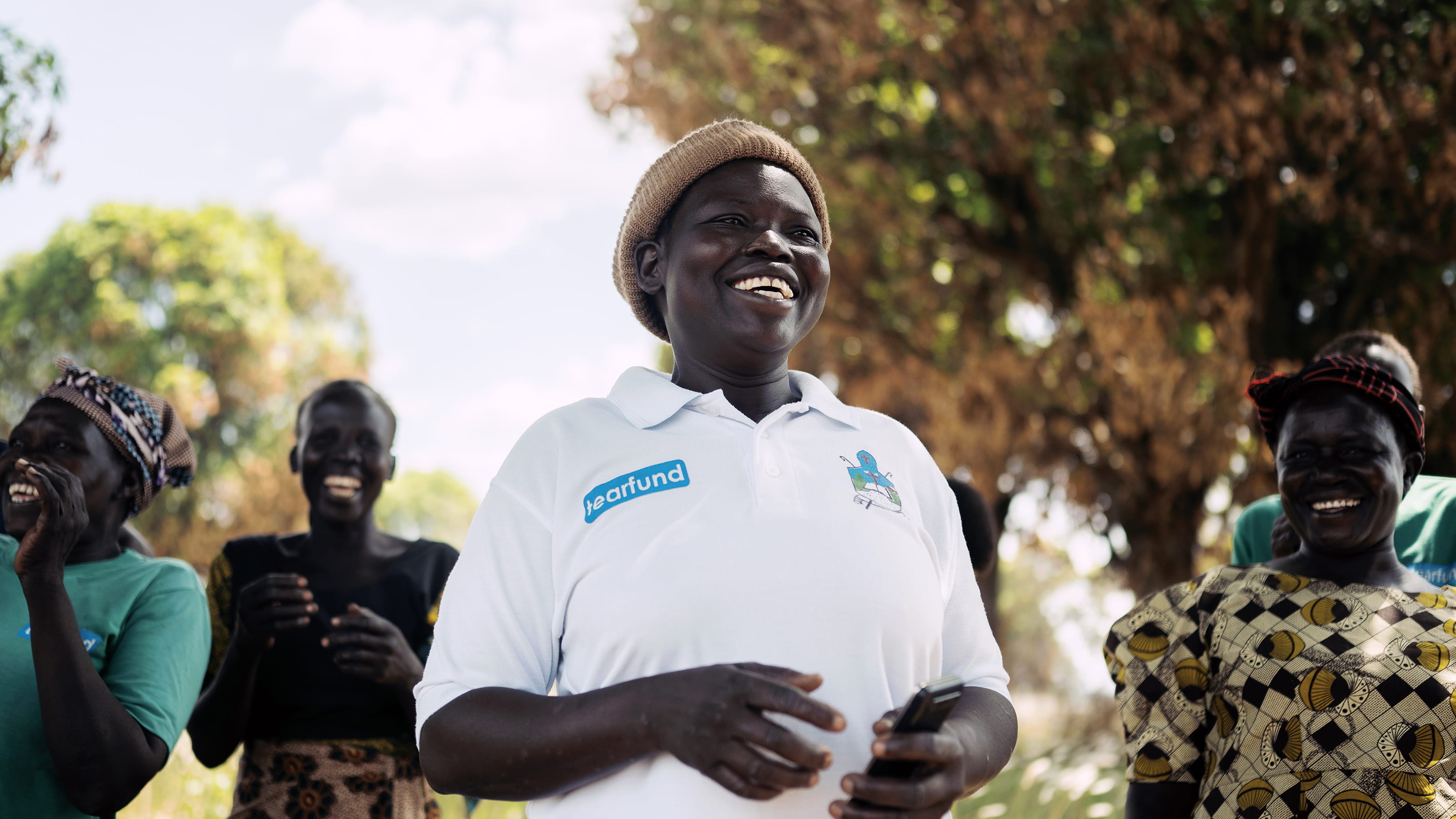 A group of smiling women with trees in the background
