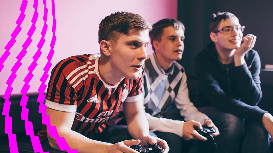 Three young men playing a football game on a games console