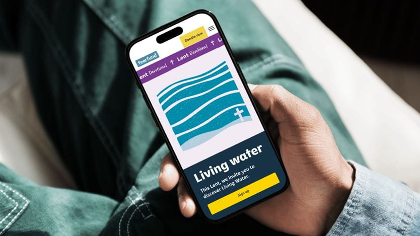 Person holds phone displaying Tearfund's "Living Water" Lent devotional page with waves and cross graphic.