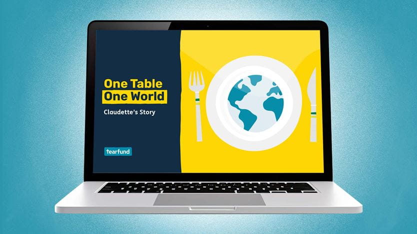 Laptop displaying "One Table One World" graphic with a globe on a dinner plate, fork, and knife.