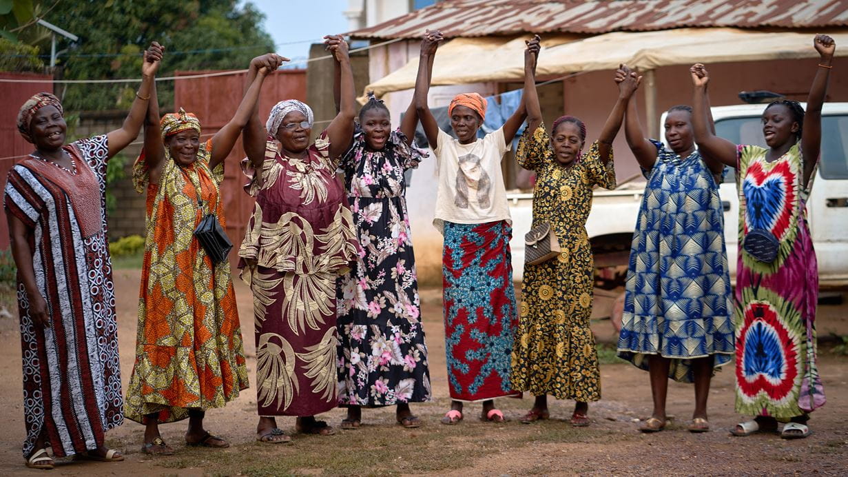 A group of women in traditional dress put their hands up in the air.