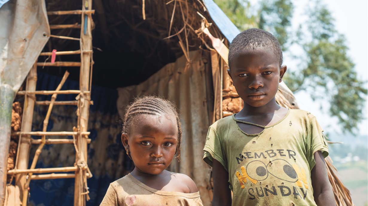 Two children outside their home