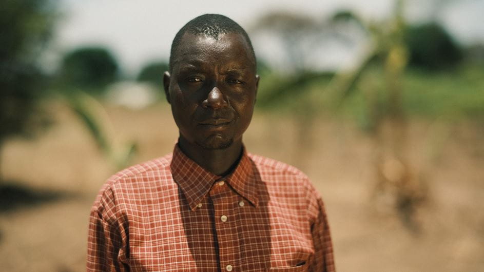 A man is standing in a field surrounded by trees.