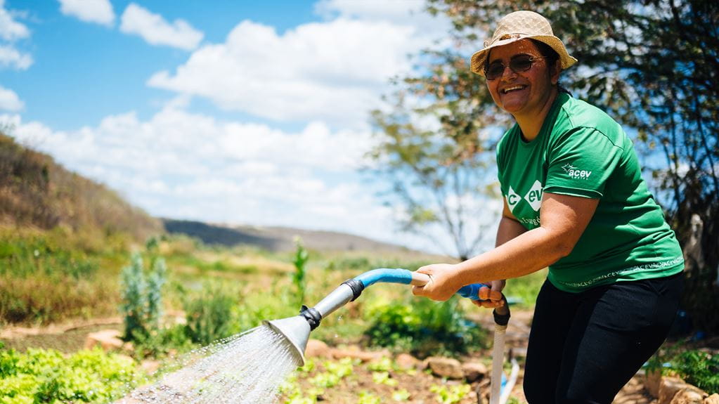 Photo of Rita watering the community garden in Sítio Glória, Paraíba State, Brazil