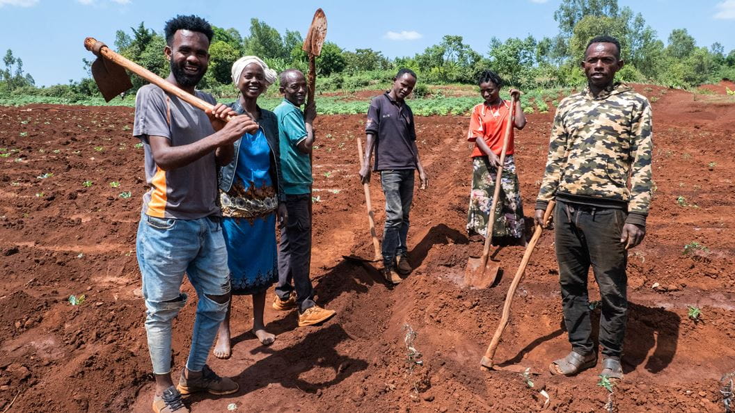 A group of people with farming tools standing in a field