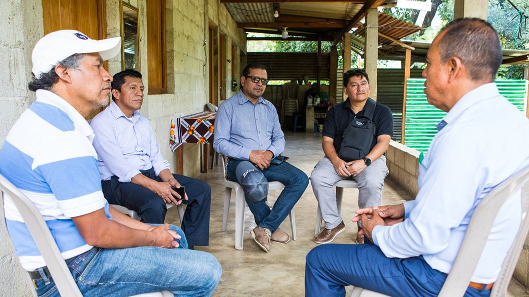 Five men sitting in chairs talking