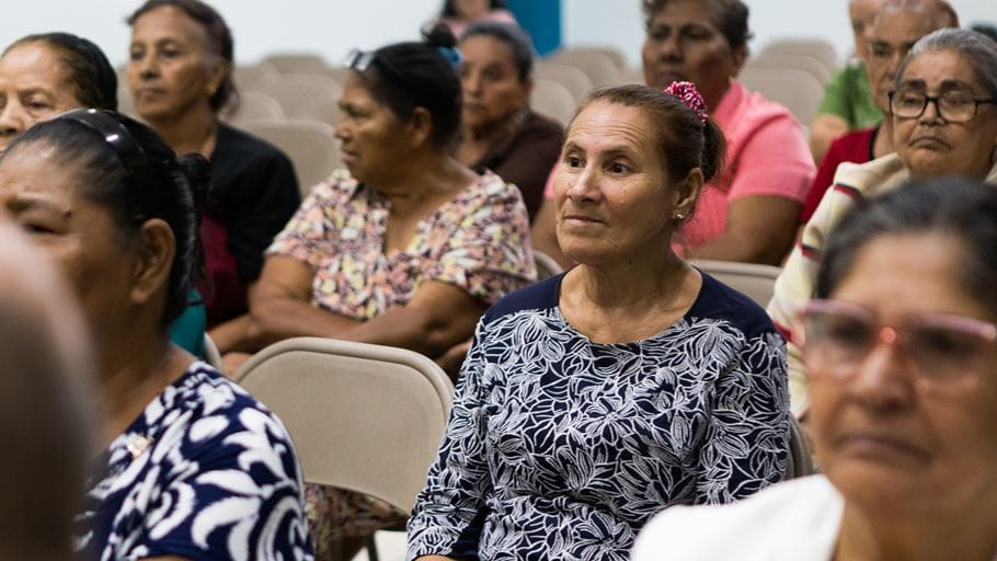 A group of older women sitting in chairs at a meeting.