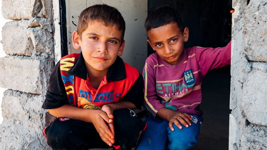 Fatima's youngest son with a friend outside her shop