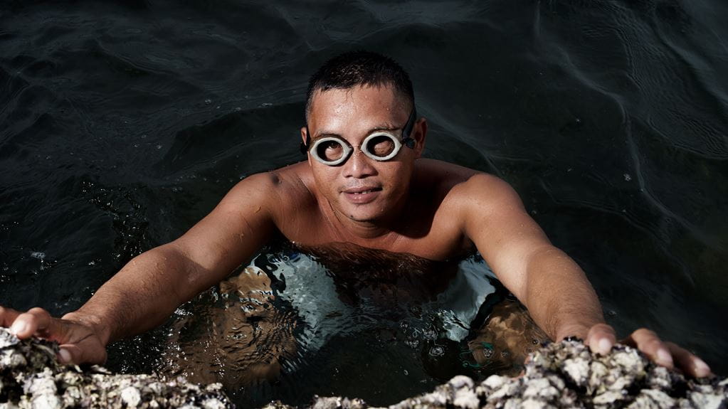 A man wearing goggle submerged in water up to his chest