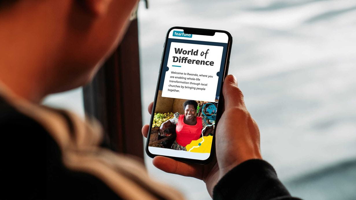 We can see over someone's shoulder that they are holding their phone. On the display is a World of Difference web page.