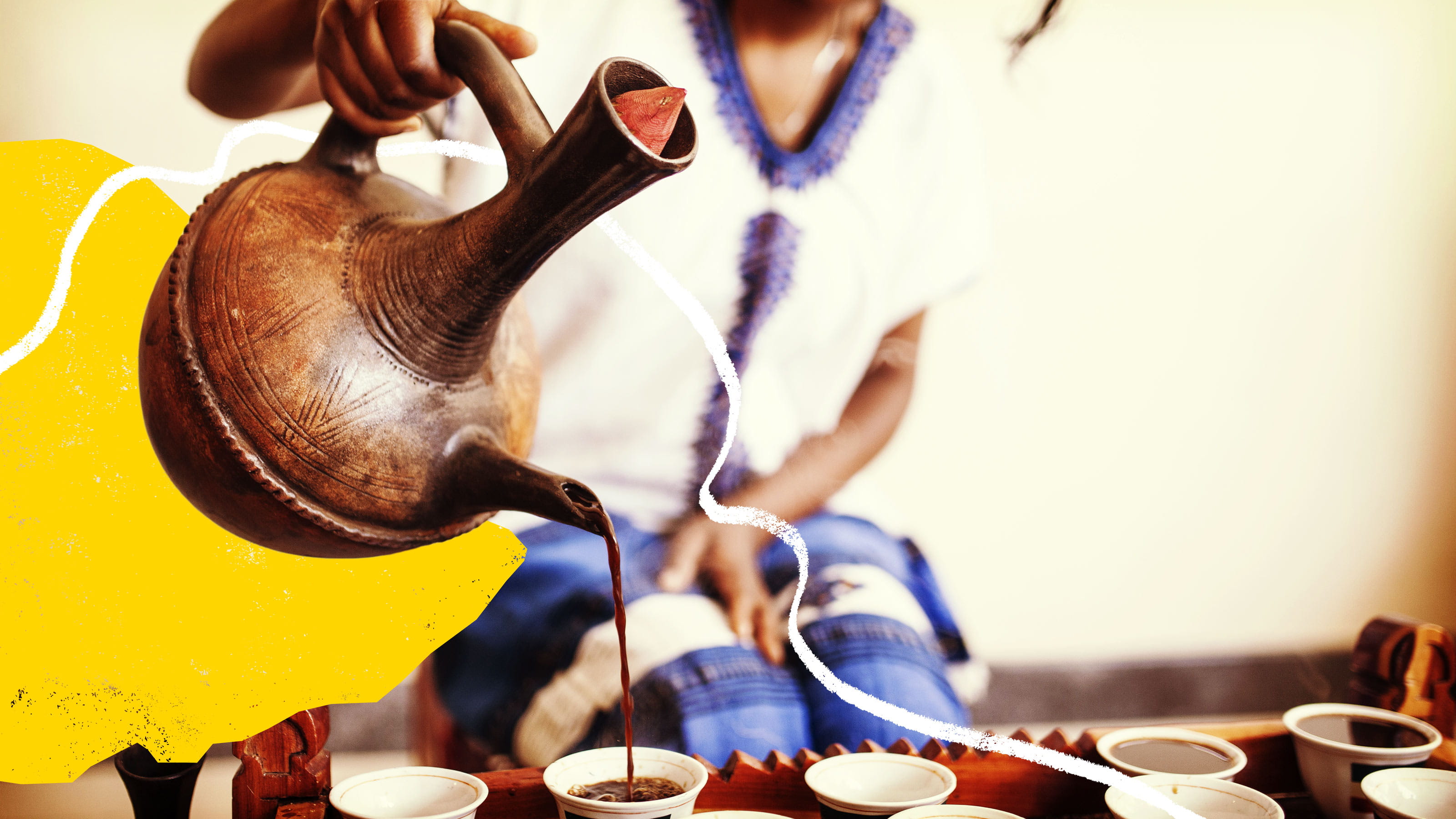 Someone out of focus pours coffee out of an Ethiopian coffee pot into cups