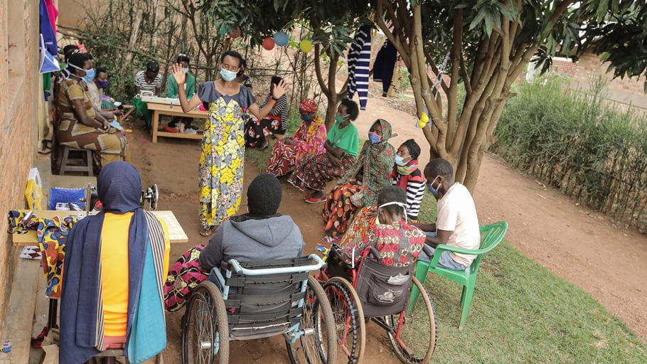 A group of 20 people praying together, as well as making crafts to help lift themselves out of poverty