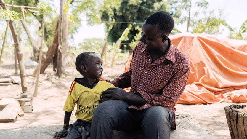 A man and a child sitting together smiling at eachother