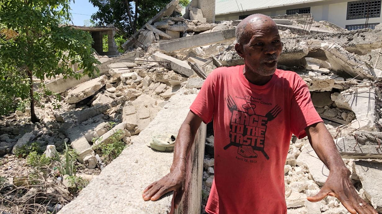 Kesner stands outside the school he has run for more than 50 years, which has been badly damaged by the earthquake | Credit: Tearfund