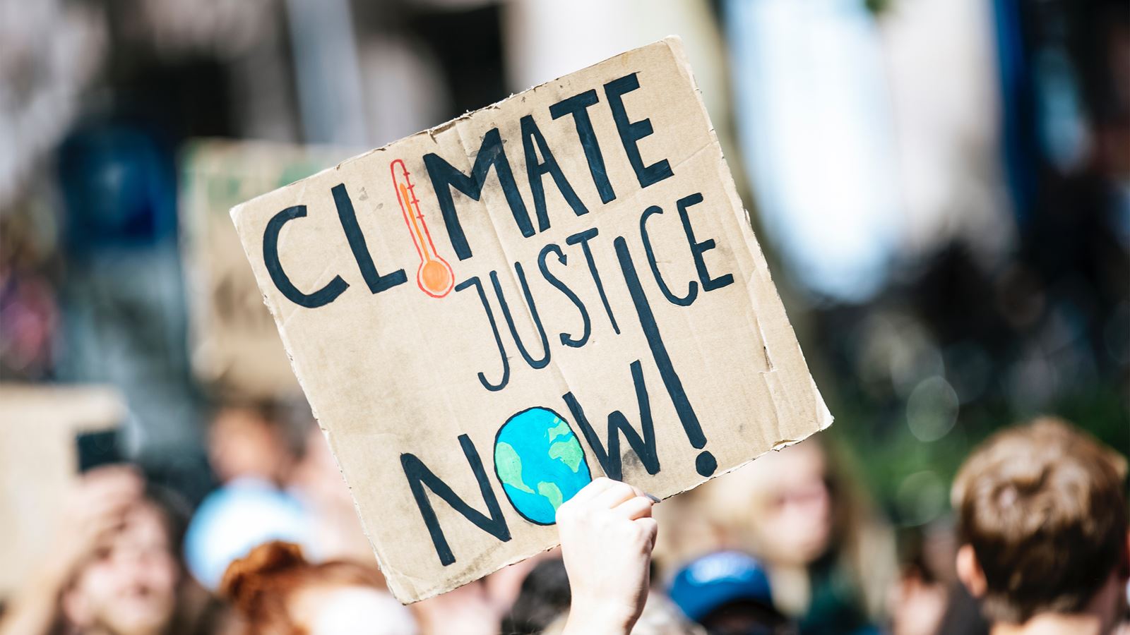 A sign at a march reading 'Climate justice now' (Unsplash/Markus Spiske)