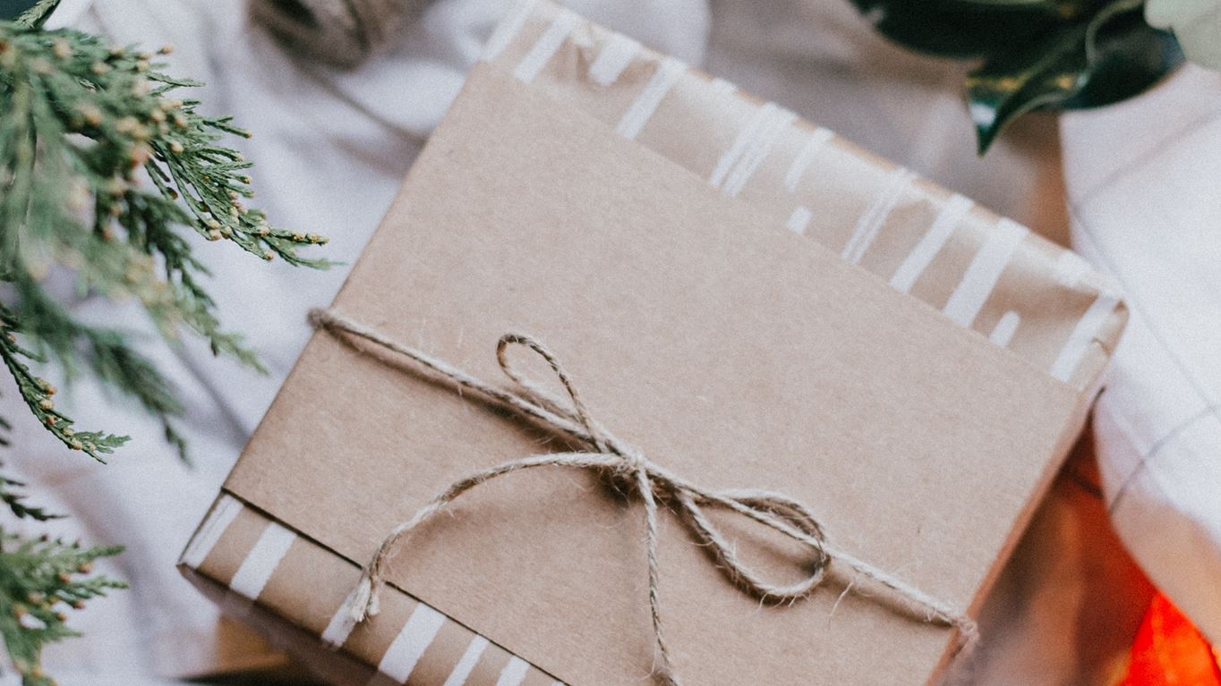 Christmas present wrapped in brown paper packaging and string (Unsplash/ Priscilla Du Preez) 