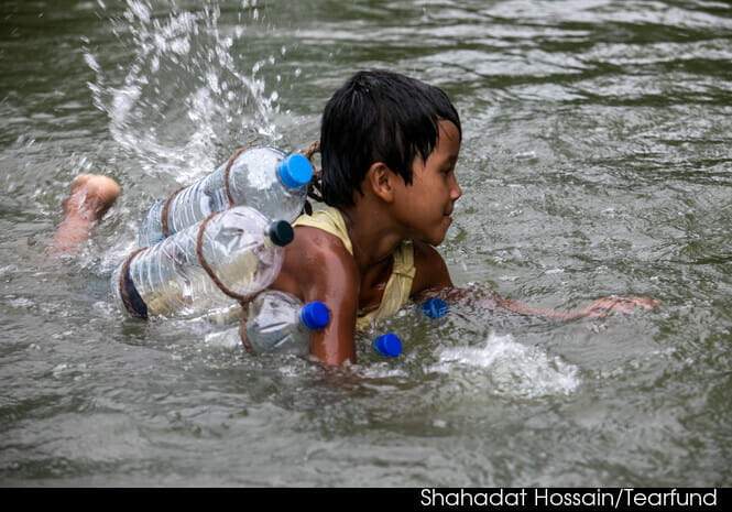 Children wearing life jackets made from plastic bottles enjoy a swimming lesson. Shahadat Hossain/Tearfund.