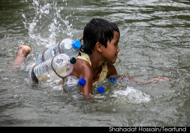 Children wearing life jackets made from plastic bottles enjoy a swimming lesson. Shahadat Hossain/Tearfund.