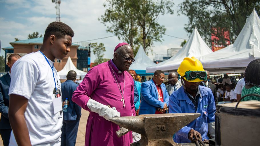 Church leader standing near an anvil with two other people