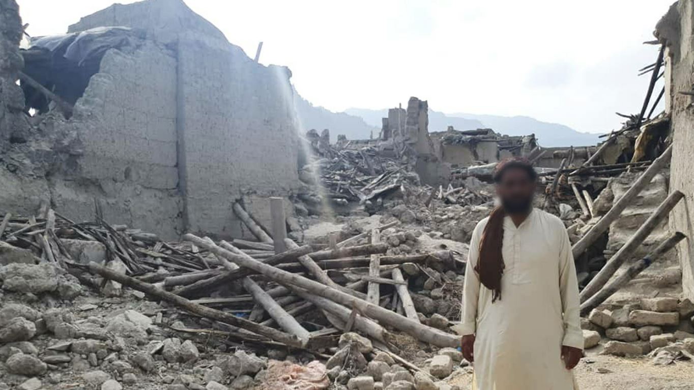 Man standing next to buildings destroyed by earthquakes