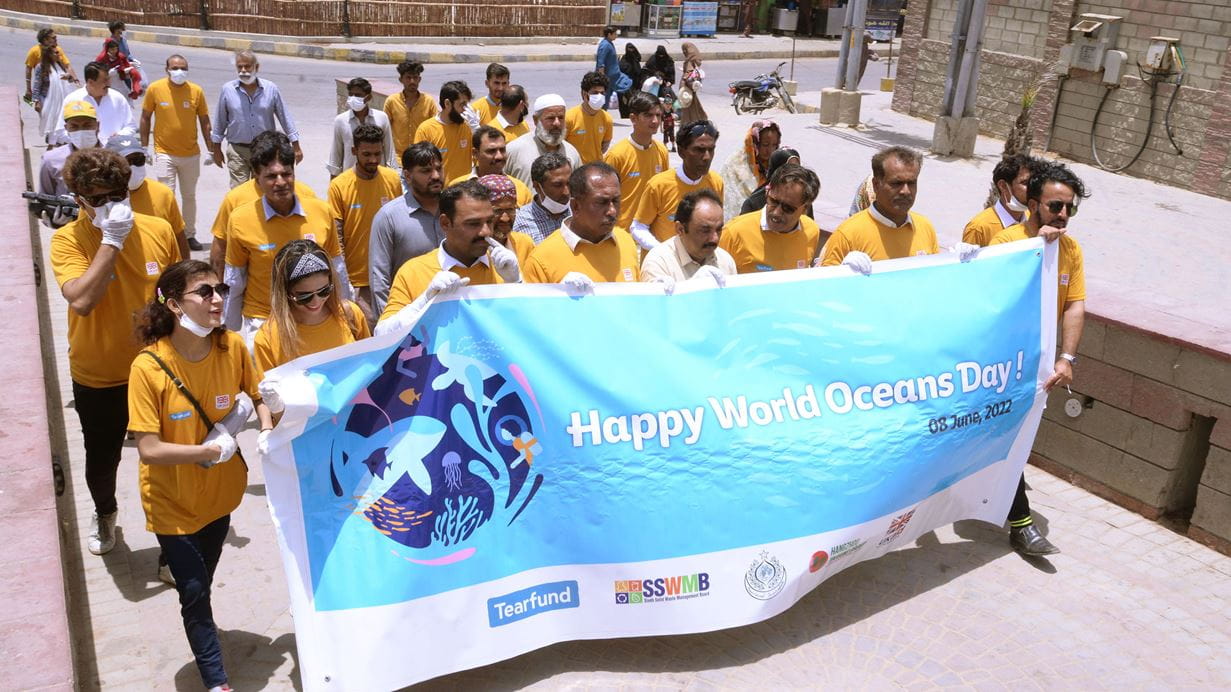 A group of people in Tearfund shirts walking together holding a sign