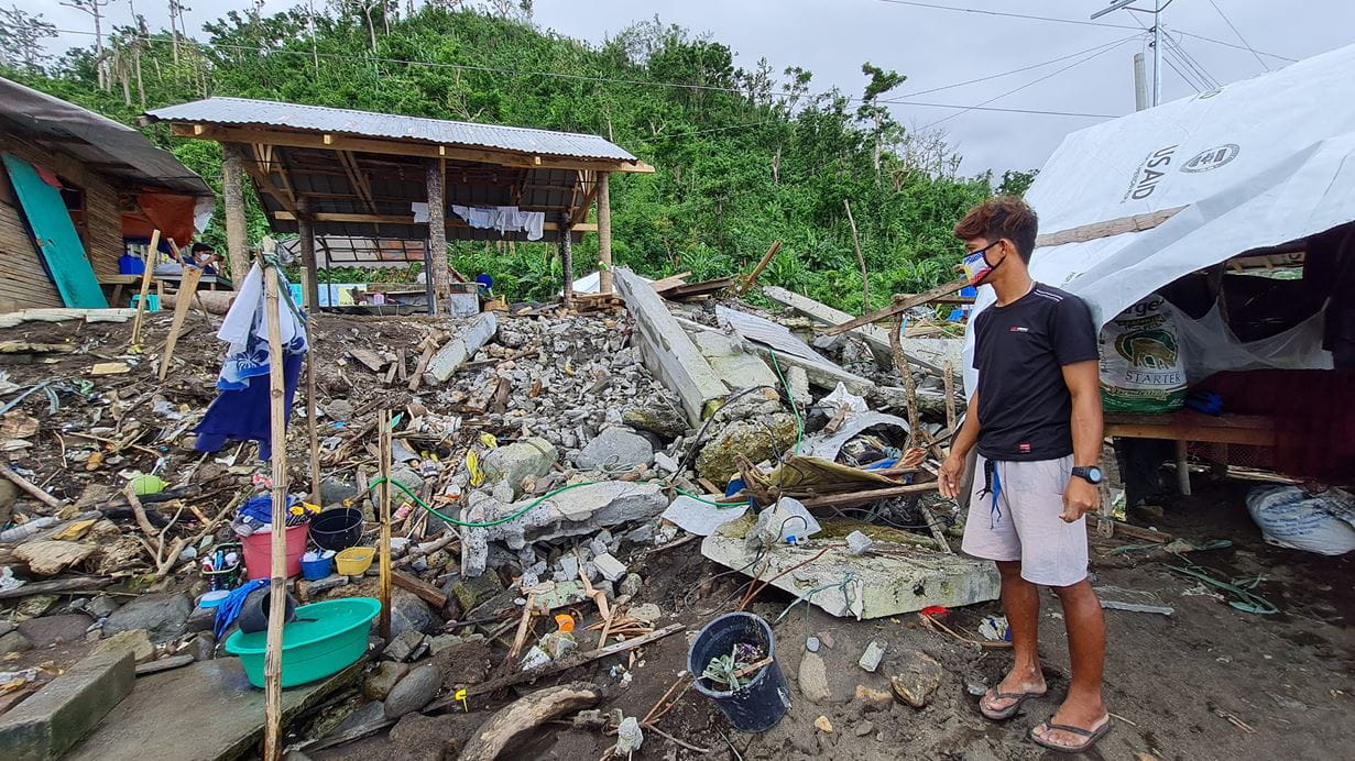 Man standing next to his home that has been destroyed by a typhoon