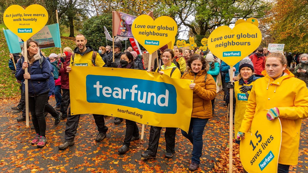 A group of people walking holding Tearfund signs