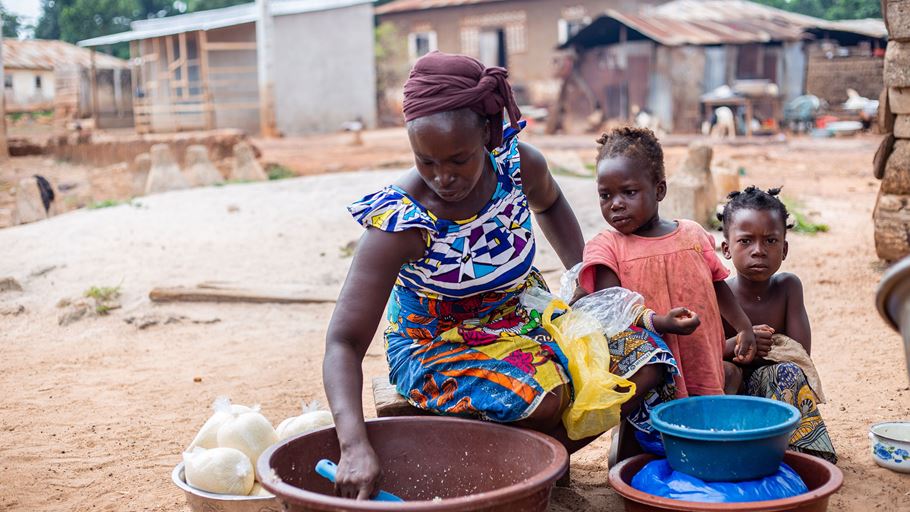 A woman packaging food with two children beside her.